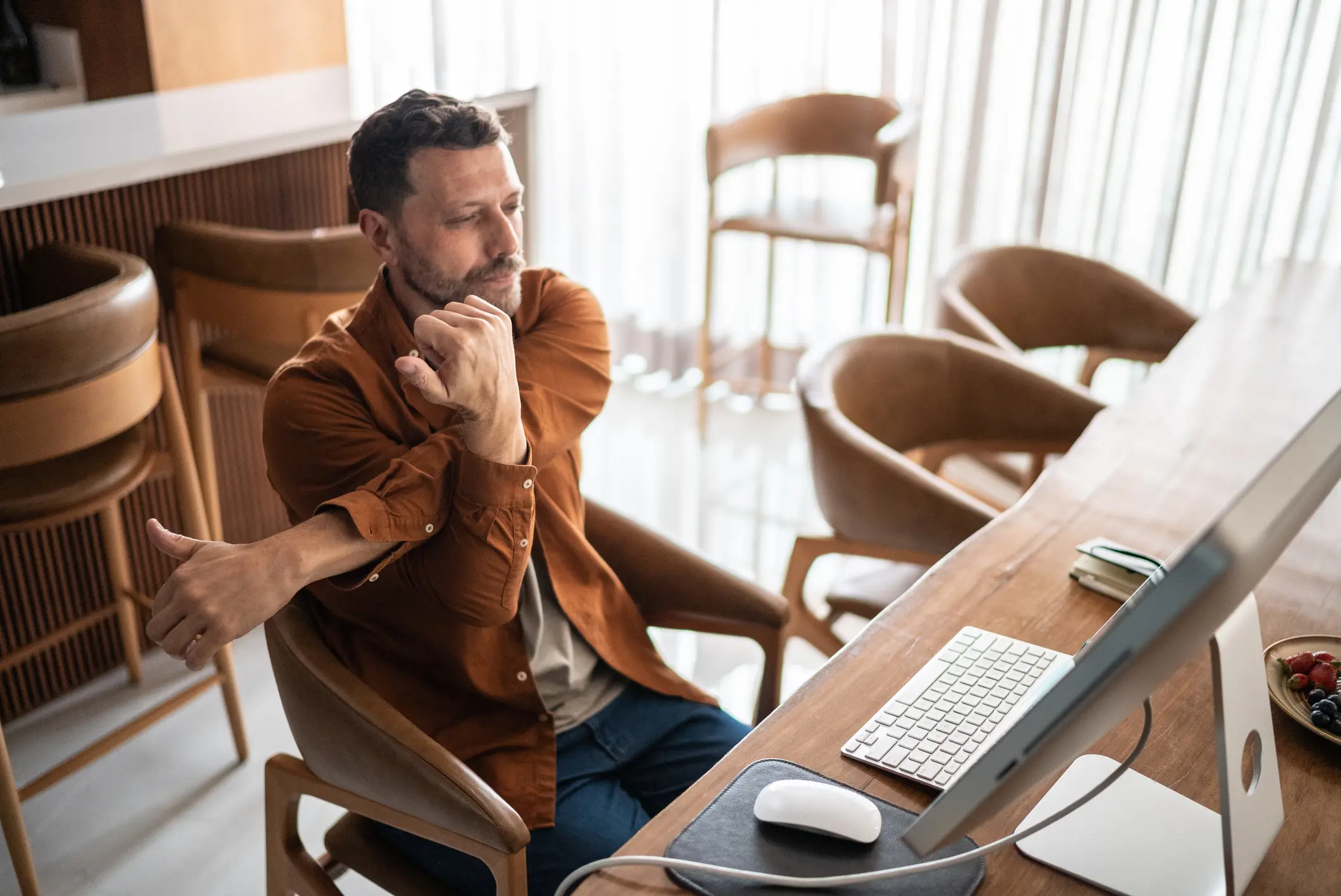 Mature man stretching in the chair while using the computer at home